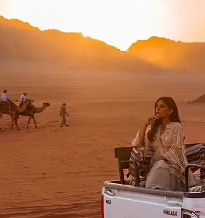 woman sitting in back of truck with camels